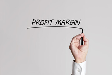 Obraz na płótnie Canvas Businessman hand with pen underlines the words profit margin on a gray background