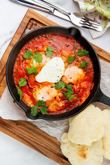 shakshuka - scrambled eggs with herbs, beans and tomatoes in a skillet with lean crispbread