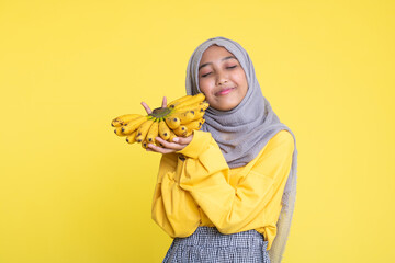 woman making fun with a banana isolated on yellow background.