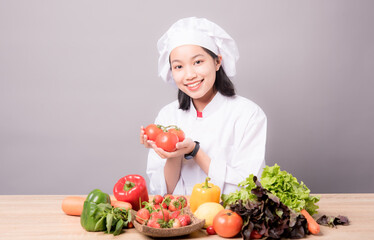 Portrait of a young Asian female chef ready to cook a new dish in the kitchen. 