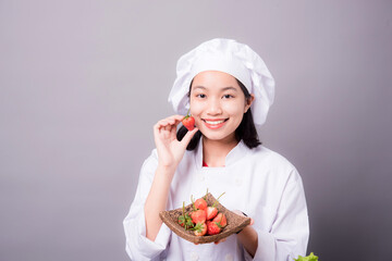 Portrait of a young Asian female chef ready to cook a new dish in the kitchen. Contains Strawberry as an ingredient