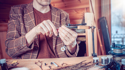 Close up on young man's hands tying a fly for fishing