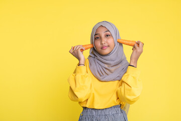 woman making fun with a carrot isolated on yellow background.