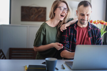 Beautiful adult couple family sitting in front of laptop video chatting online at home