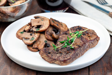 Beef filet with sauteed brown mushrooms and thyme, on wooden background, horizontal