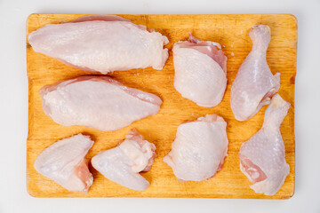 butchered carcass of raw chicken on a wooden cutting board on a white background