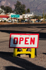 Rustic wooden "Open" sign on street next to storefront