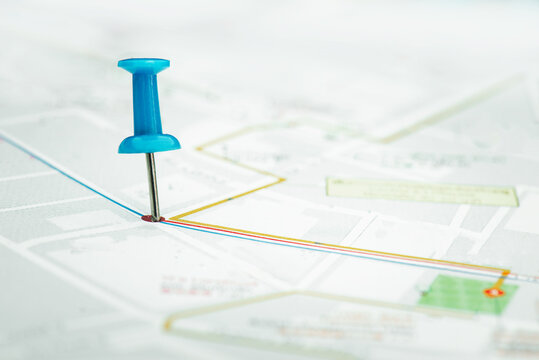 The blue pin is placed on a paper map where the blue line and other colors are linked. This point seems to be an intersection. Which is the destination of planning.