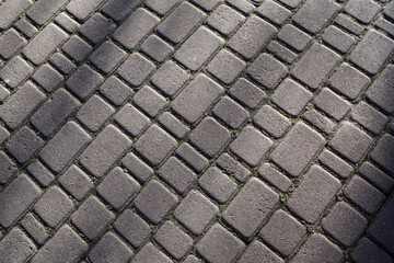 Texture of stone paving stones. Cobblestone diagonal pavement road at sidewalk. Hard surface. Stone pavement in perspective. Granite cobblestone. Abstract background of cobblestone pavement close-up