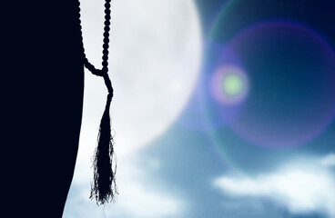 Silhouette of Muslim woman praying with prayer beads on his hands