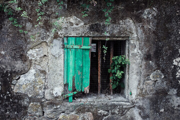old broken green window with rusty gratings