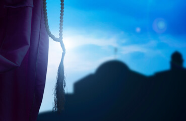 Silhouette of Muslim woman praying with prayer beads on his hands