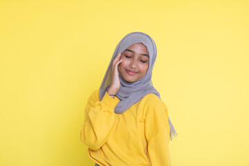 Fashion portrait of young beautiful asian muslim woman with wearing hijab isolated on yellow background.