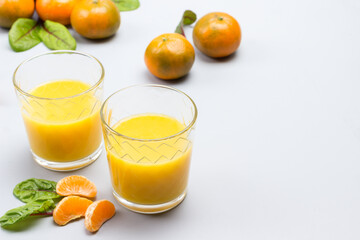 Fototapeta na wymiar Two glasses with citrus juice. Tangerines on table
