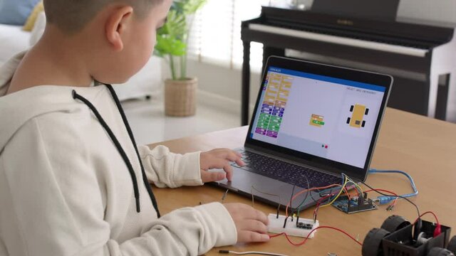 Young Asia Student Remotely Learn Online At Home In Coding Robot Car And Electronic Board Cable In STEM, STEAM, Mathematics Engineering Science Technology Computer Code In Robotics For Kids Concept.