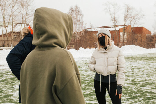 A Group Of Masked Athletes Talking To Each Other. People In Medical Masks Communicate On The Street In Winter 