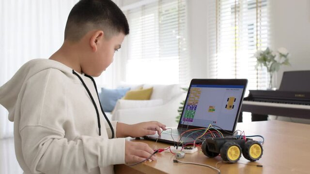 Young asia student remotely learn online at home in coding robot car and electronic board cable in STEM, STEAM, mathematics engineering science technology computer code in robotics for kids concept.