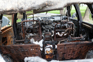 Fototapeta premium The interior of burnt-out car. Melted plastic of dashboard and rusted remains of seats. Selective focus
