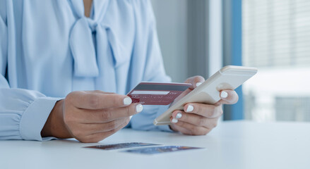 The businesswoman's hand is holding a credit card and using a smartphone for online shopping and internet payment