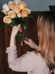 Florist, a flower girl with pruning shears in her hand, collects a bouquet of roses.