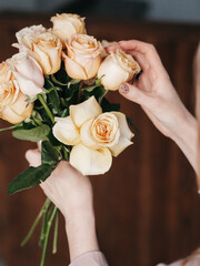 A florist makes a composition, a flower girl with a pruner in her hand, collects a bouquet of roses.
