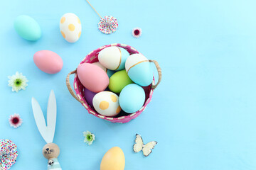 Fototapeta na wymiar Cute bunny next to easter colorful eggs over pastel background