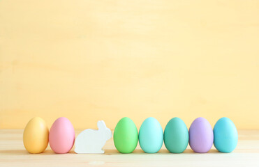 Cute bunny next to easter colorful eggs over pastel background