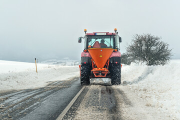 Small gritter maintenance tractor spreading de icing salt on asphalt road, view from car driving...