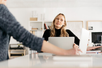 Thoughtful young businesswoman chatting to a colleague