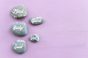 zen stones with the words Mind body soul. purple wooden background