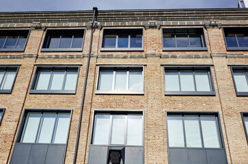 Brick building with windows and downspout against blue sky