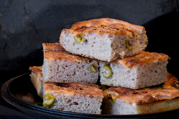 Pieces of fresh soft moist sourdough focaccia with green olives
