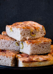 Pieces of fresh soft moist sourdough focaccia with green olives