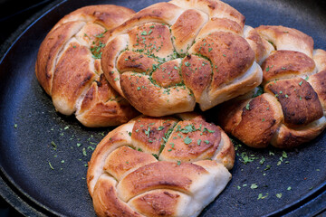 Soft warm home made braided bread rolls seasoned with garlic paste and dressed with parsley
