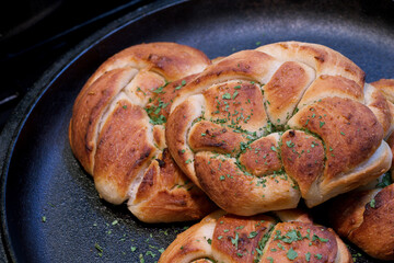 Soft warm home made braided bread rolls seasoned with garlic paste and dressed with parsley