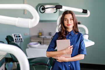 Young doctor in a dental clinic. Portrait of young female doctor dentist with digital tablet in...