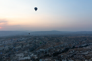 Hot air balloons over the rocks on sunrise with empty blue sky