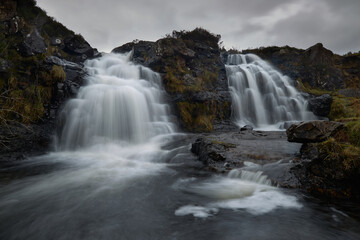 double waterfall in river with silky water. dry autumn grass- Fairy Pools - Skye Island - Scotland - Uk