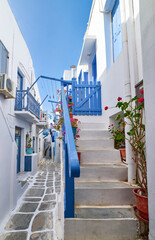 Romantic traditional narrow cobbled streets of Greek island towns. Whitewashed houses, flower pots, blue balconies, stairs and doors. Mykonos, Greece