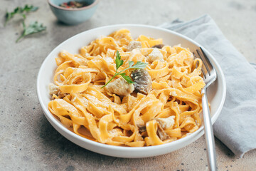 Italian pasta fettuccine alfredo with chicken, mushrooms and sause on plate on stone table. Closeup.