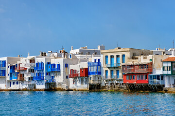 Fototapeta na wymiar Seafront Little Venice of Mykonos town or Chora, Cyclades, Greece. Bars, cafes, restaurants in whitewashed old houses hang on cliffs above sea waves.