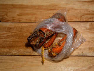 Rotten carrots in bag on wooden surface