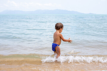 adorable toddler toddler has fun playing on sandy beach of tropical sea