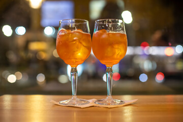 Two glasses of wine with orange coctail stand on a wooden table in a cafe.Italian alcoholic drink with oranges and ice. Close-up, selective focus