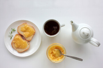 Flat lay food composition with cup of herbal tea, teapot and toast with honey on white table background. Healthy breakfast concept. Top view