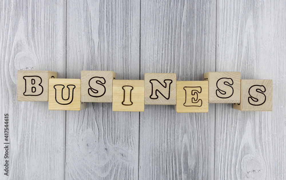Fototapete Wooden blocks with letters spelling - Business - in a conceptual image in an overhead view on grey wood planks with copyspace. Flat lay, top view