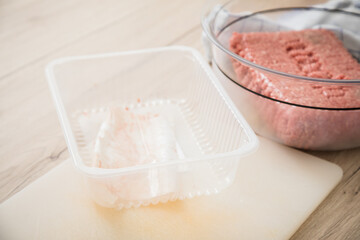 Fototapeta na wymiar Hackfleisch halb und halb roh von Rind und Schwein aus Plastik Verpackung in Schale auf Schneidebrett zum Kochen in Küche