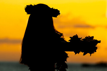 Silhouette of a Hawaiian woman dancing during sunset near the sea.  - obrazy, fototapety, plakaty