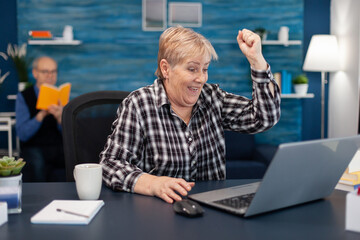 Portrait of cheerful mature woman celebrating achievement. Thrilled cheerful elderly woman while...