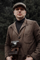 photographer with a retro camera in his hands. Dressed in retro style, jacket and cap - 417547062